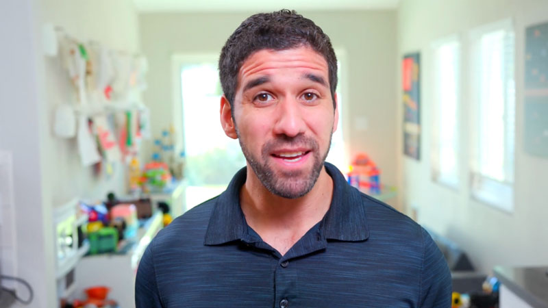 Man in dark polo shirt speaking in colorful playroom